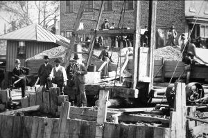 Black and white photo of men on a wooden bridge outcropping