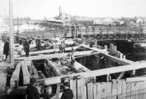 Black and white photo shows several workmen on a wooden structure