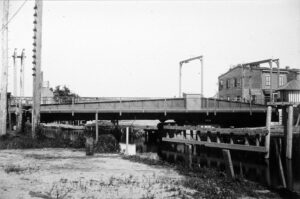 Black and white photo of a low bridge over a creek