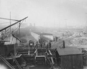 Aramingo Sewer tunnel, workmen, pilings, machinery, Beach St. Bridge in distance