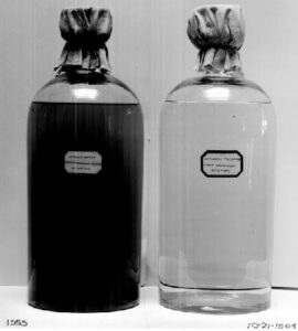 Two bottles of water from a river, one dark with pollution and one clear after filtration
