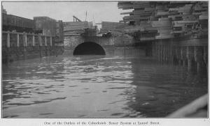 Black-and-white image showing sewer outlet, retaining walls and body of water