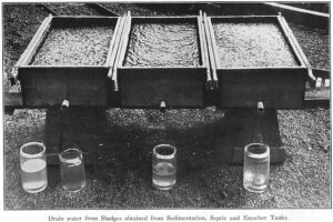 Black-and-white image of a tray with three compartments and four small glass cylinders