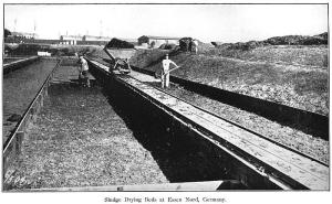 Black-and-white photo of a man standing in a long trench